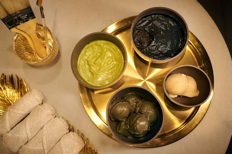 Spa treatment display with gold tray containing five skincare products and cream towels