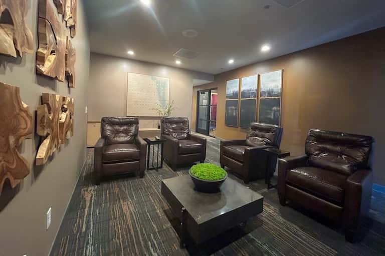 Modern lounge with leather recliners, decorative wall art, large windows with city views, and contemporary decor