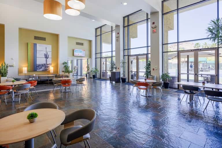 Modern hotel lobby with polished floor, contemporary seating, large windows, and yellow accent wall