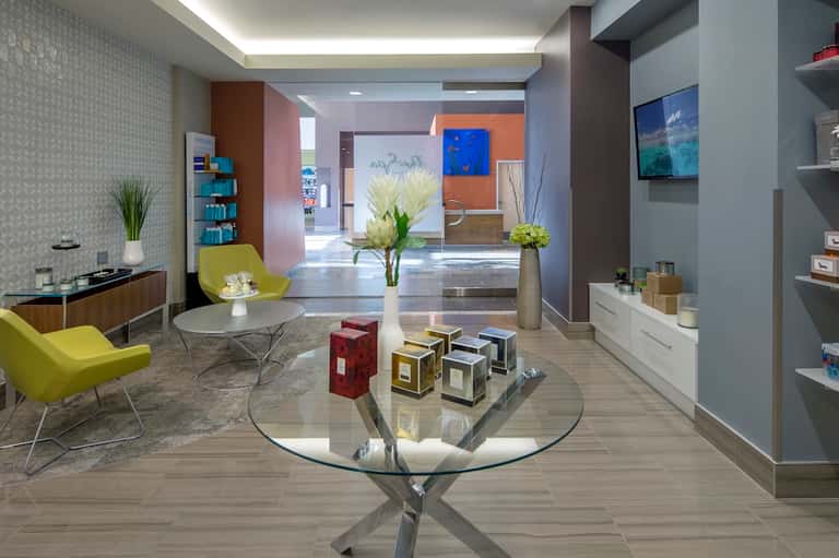 Modern hotel lobby with yellow chairs, glass table, colorful accent walls, and bright natural light