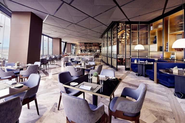 Upscale restaurant with marble floors, modern seating, and floor-to-ceiling windows