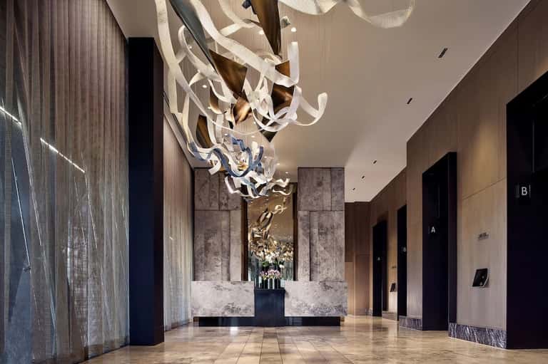 Luxurious hotel corridor with dramatic white ribbon chandelier and marble accent wall