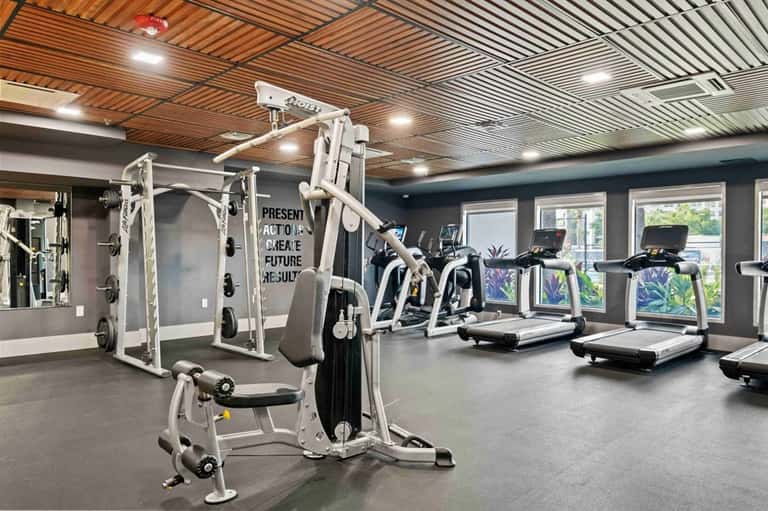 Modern fitness center with cardio equipment, weight machines, wood ceiling, and glass doors