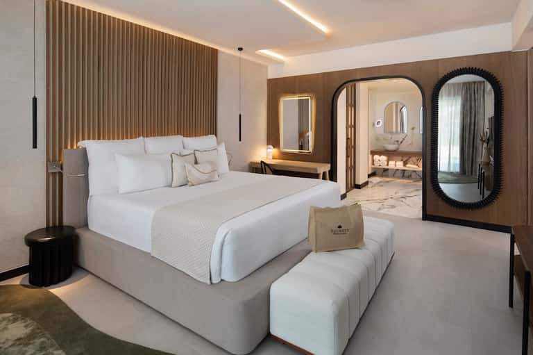 Luxury hotel suite with platform bed, en-suite bathroom, and decorative mirrors