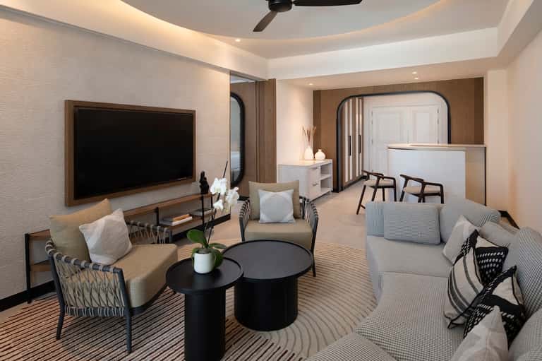 Luxury hotel suite living area with flat-screen TV, modern furniture, and elegant neutral decor