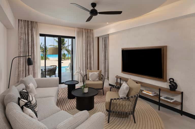 Luxury resort suite with ocean view, modern furnishings, and sliding glass doors