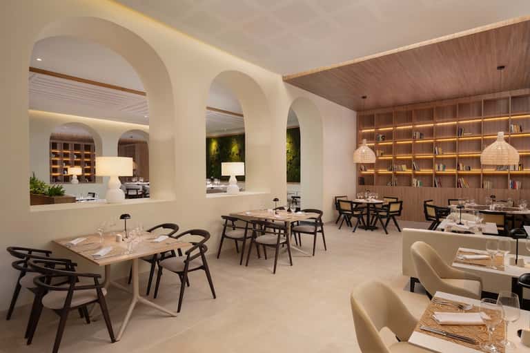 Contemporary restaurant interior with white archways, wood shelving, modern lighting, and minimalist dining tables