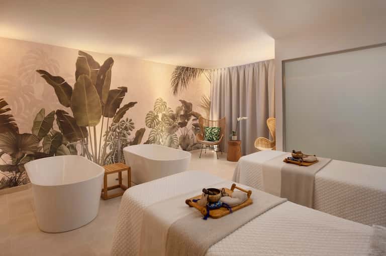 Contemporary spa treatment room with freestanding white tubs and botanical wall mural