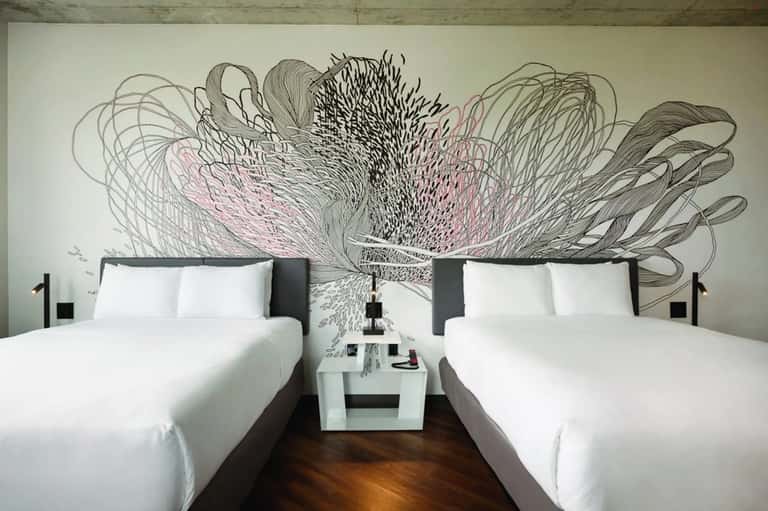 Modern hotel room with two queen beds and artistic black and pink wall mural