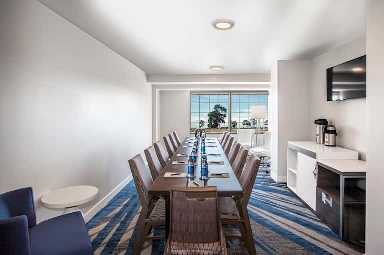 Contemporary conference room with long dining table, windows, and water views
