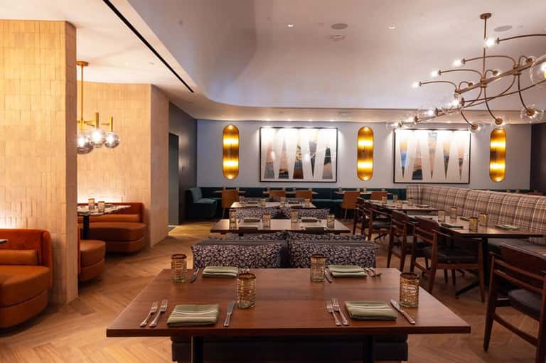 Elegant restaurant dining room with wood accents, artistic wall displays, and lounge seating