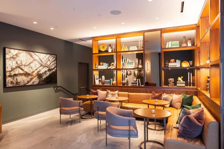 Contemporary lounge with illuminated wooden shelving, gray walls, mid-century furniture, and ambient lighting