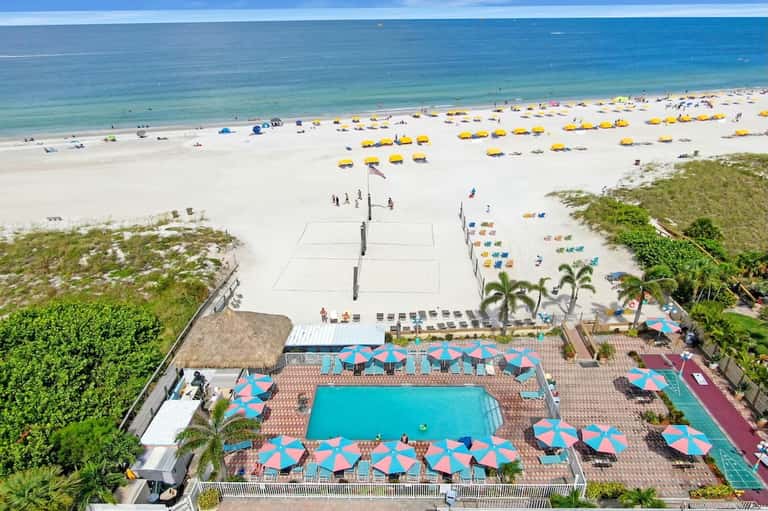 Elevated view of beachfront pool with umbrellas, beach volleyball net, and ocean access