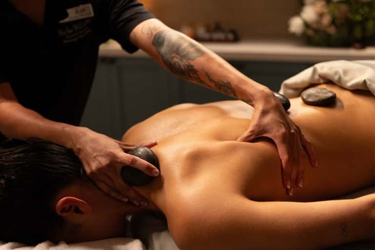 Professional massage therapist performing stone massage treatment on client's back