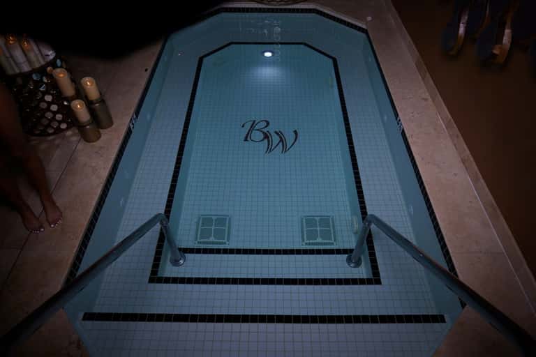 Indoor spa pool with blue tile, logo branding, and ambient lighting