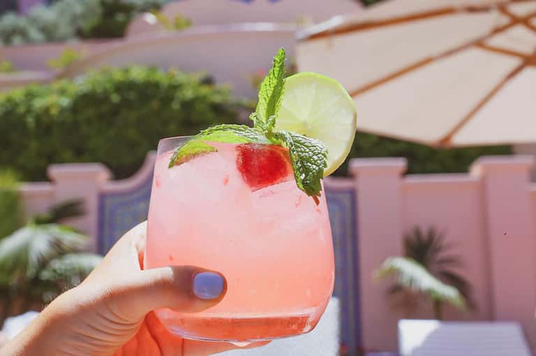 Pink cocktail with lime wheel and fresh mint garnish at poolside resort