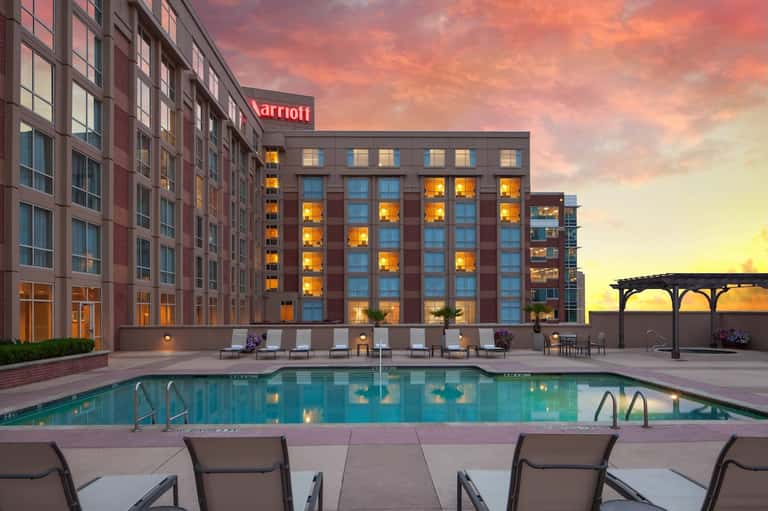 Marriott hotel rooftop pool at sunset with illuminated brick building and city backdrop