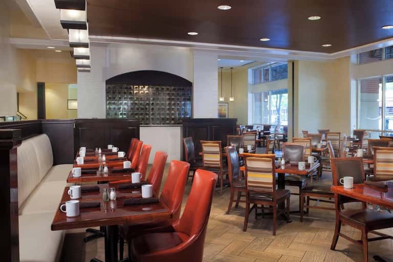 Hotel restaurant dining room with booth seating, wood accents, and modern ceiling design