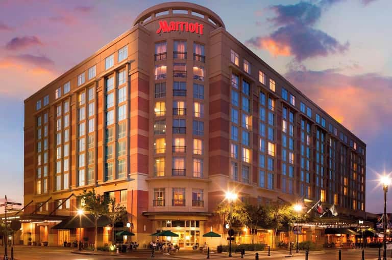 Red brick Marriott hotel building illuminated at dusk with curved corner architecture and ground-level retail