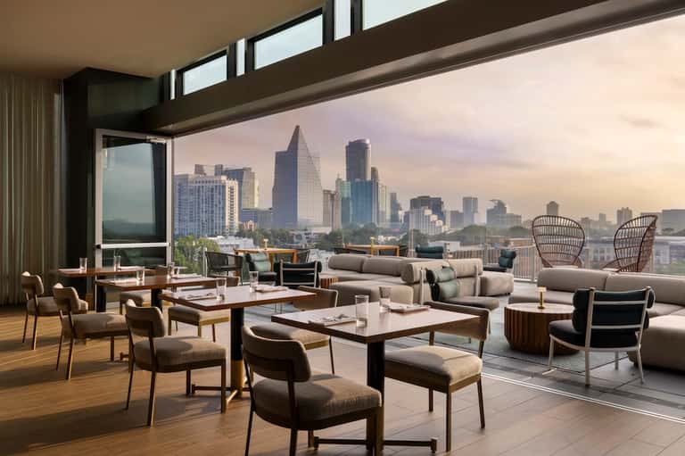 Luxury penthouse lounge with floor-to-ceiling windows showcasing expansive city skyline views and contemporary furnishings