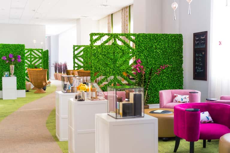 Contemporary spa or retail space with green living walls, pink seating, and white display pedestals