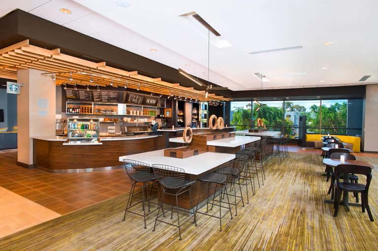 Modern café lounge with Starbucks counter, high seating, and floor-to-ceiling windows