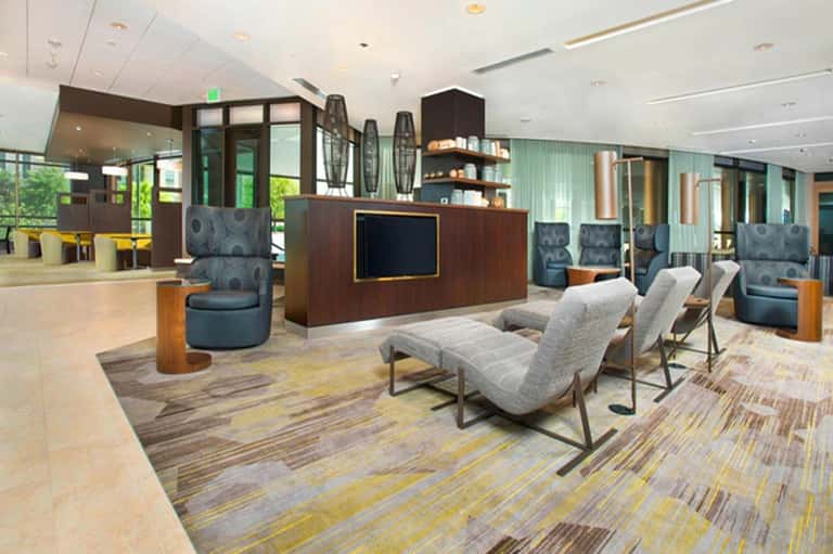 Contemporary hotel lobby with reception desk, seating areas, modern decor, and accent lighting