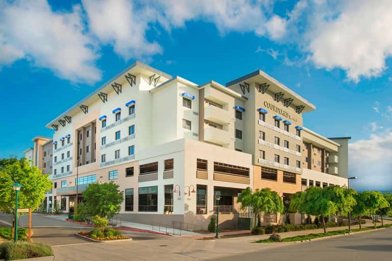 Contemporary hotel building exterior with cream and tan facades under blue sky