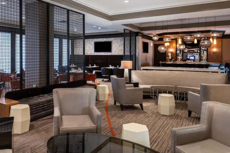 Upscale hotel lounge with modern furnishings, bar counter, pendant lighting, and decorative screens