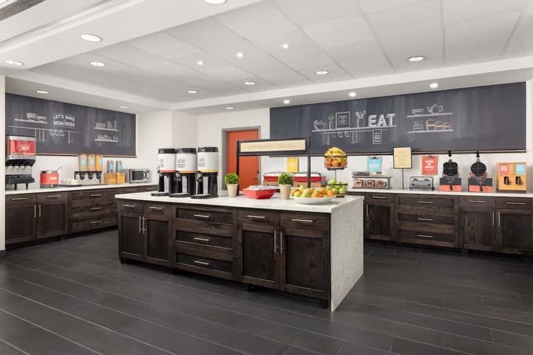 Hotel breakfast or dining area with dark cabinetry, chalkboard walls, and food service counter