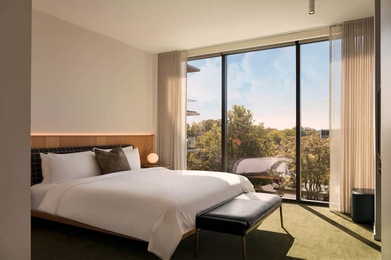 Modern bedroom with king bed, nature views through floor-to-ceiling sliding glass doors
