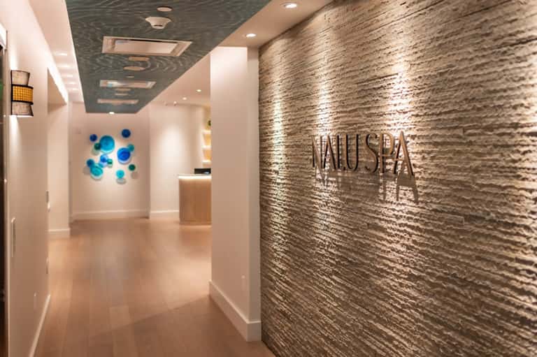 Modern spa entrance hallway with stone accent wall, signage, and contemporary lighting