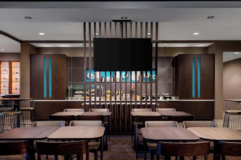Modern hotel restaurant interior with dark wood design, blue accent lighting, and table seating