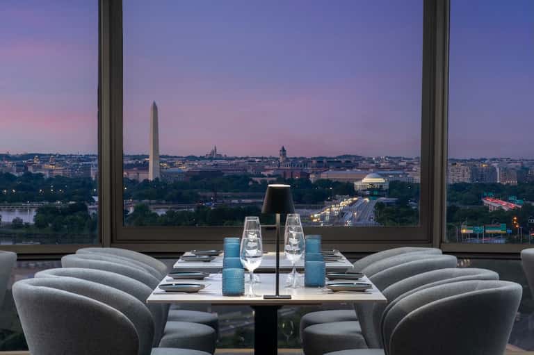 Fine dining restaurant with panoramic windows overlooking Washington DC monuments at dusk