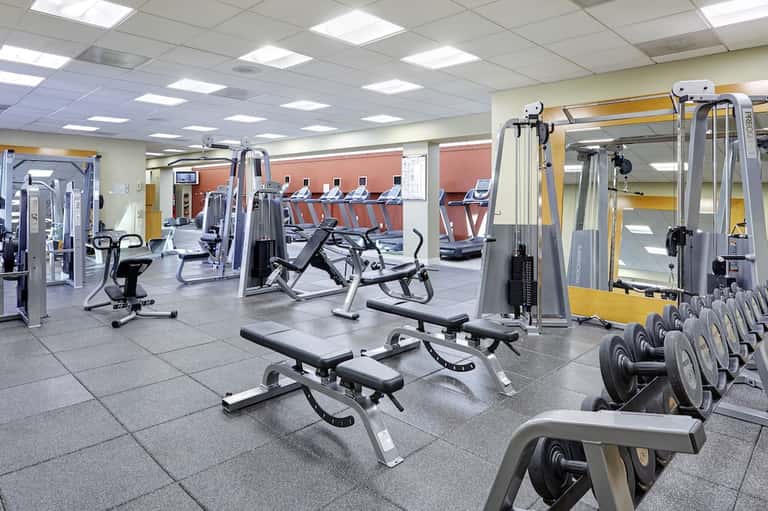 Spacious fitness facility with weight machines, dumbbells, treadmills, and exercise equipment on tiled floor