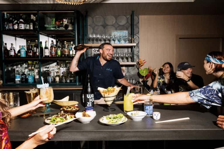 Lively bar scene with bartender serving drinks and food to guests at counter