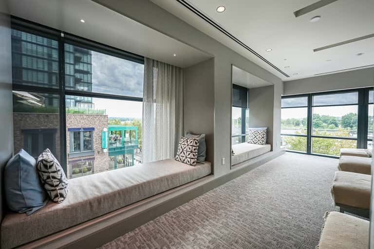 Luxury suite with floor-to-ceiling windows, dual window seats, modern furnishings, and panoramic landscape views
