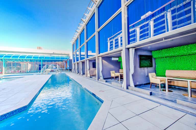 Indoor pool facility with lap lanes, blue water, glass walls, and modern lounge seating