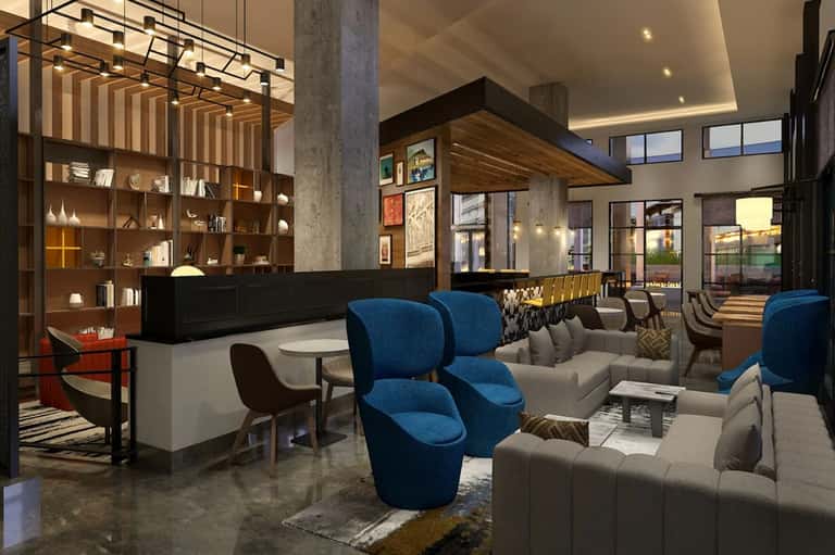 Modern hotel lobby lounge with blue accent chairs, wooden shelving, and contemporary furnishings