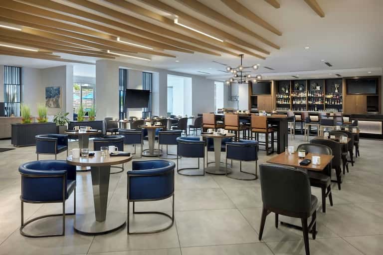 Contemporary resort lounge with navy chairs, round tables and full bar in background