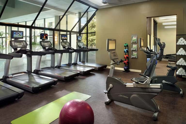 Modern hotel fitness center with treadmills, exercise bikes, mirrored walls, and exercise ball