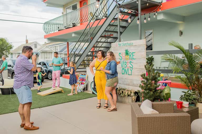 Family gathering outside colorful beachfront property with orange and green architectural features