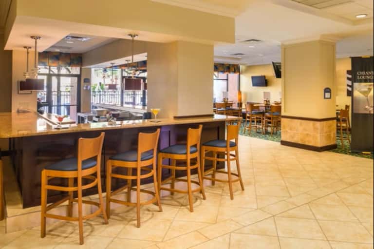 Hotel bar and lounge with wooden bar counter, yellow walls, and seating areas