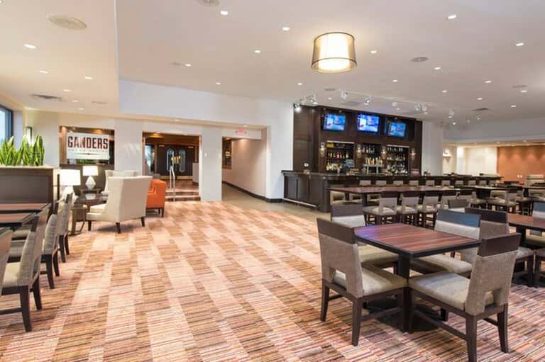 Hotel lobby lounge with bar, seating areas, modern furnishings, and open layout with signage