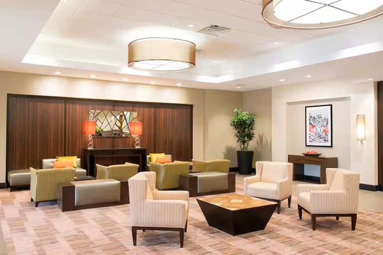 Elegant hotel lobby with cream chairs, dark wood accents, fireplace, and modern lighting
