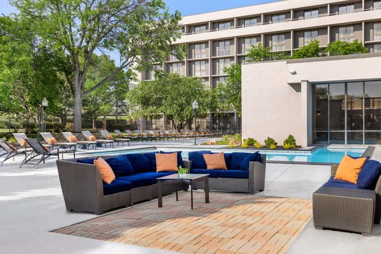 Resort courtyard with modern lounge seating, pool, and landscaped trees overlooking the building