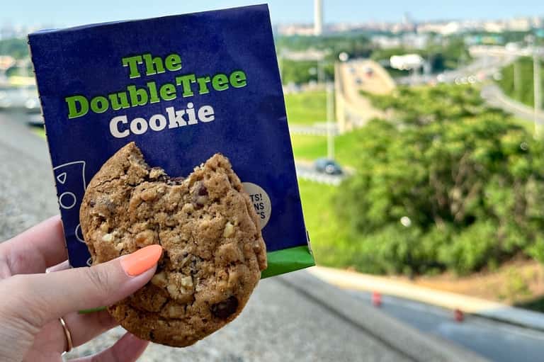Hand holding DoubleTree cookie package with cityscape visible in background