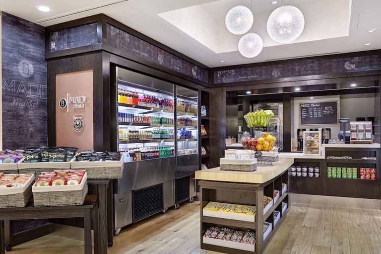 Hotel market cafe with refrigerated displays, fresh produce, and pendant lights