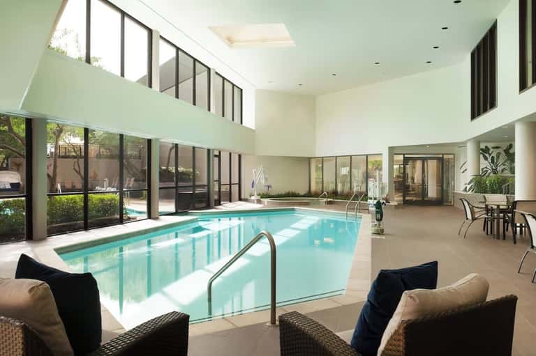 Indoor heated pool facility with high ceilings, natural light, and modern comfortable seating