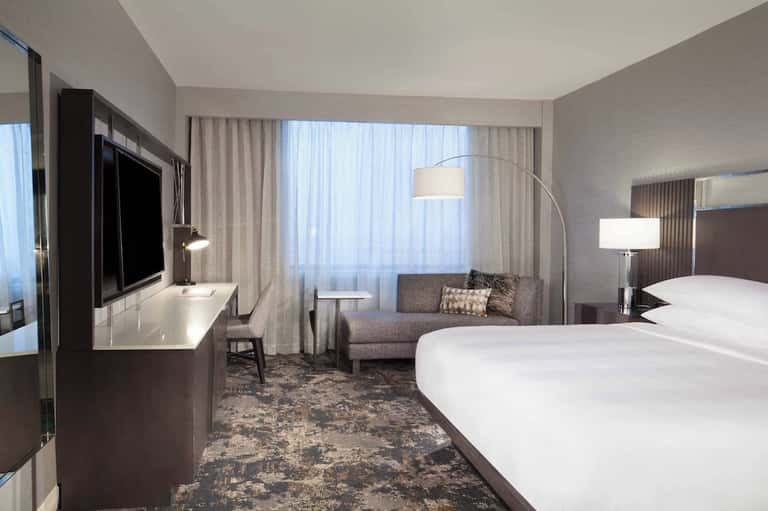 Contemporary hotel room with two queen beds, living area, flat-screen TV, and city views